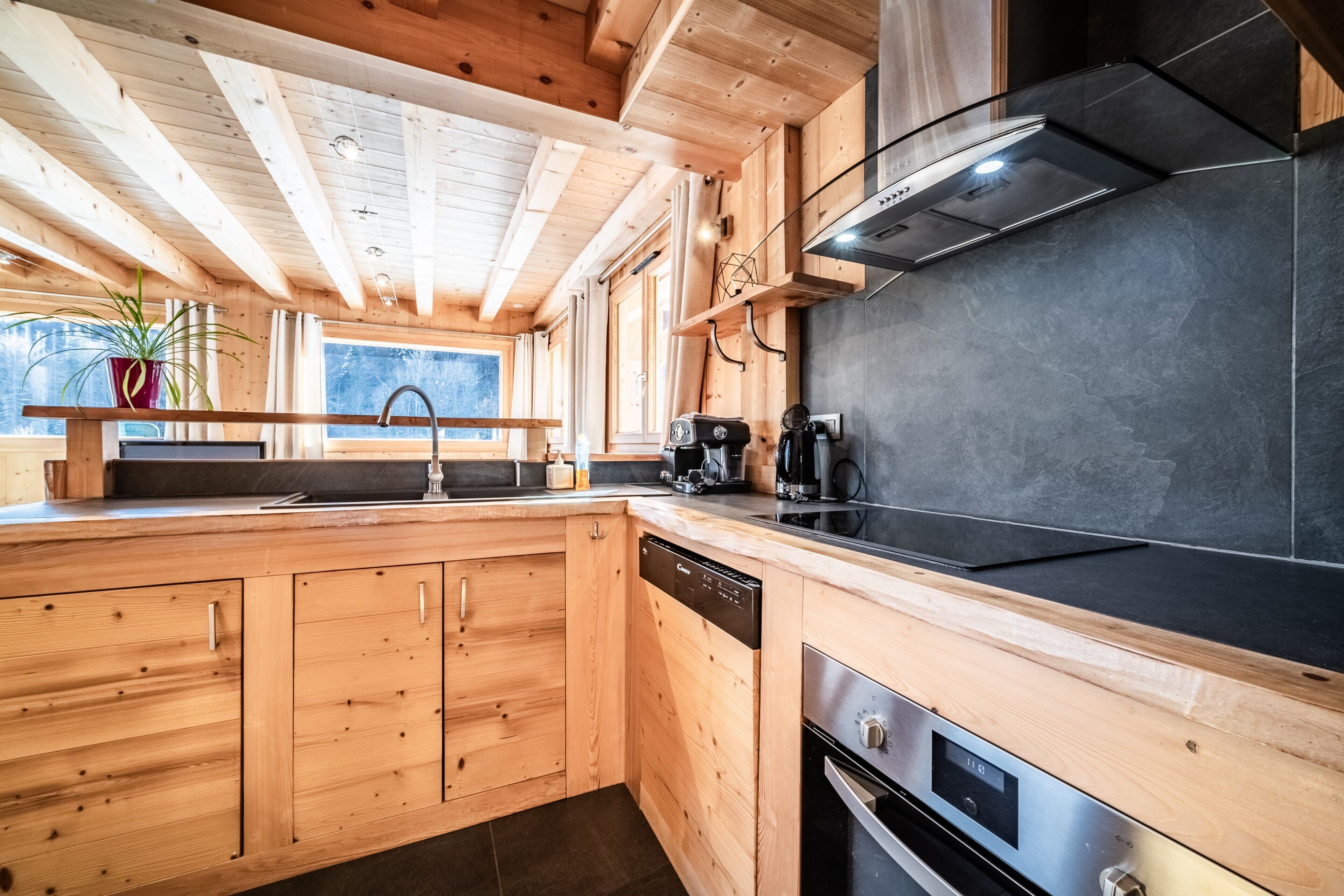 Een keuken met houten kastjes, een vaatwasser, een fornuis en een zwart aanrecht.