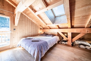 A wooden cabin with a loft bedroom, a skylight, and a bed with pillows. - Chalet 'Le Mas Devant' with Mountain View, Private Terrace and Wi-Fi (Morillon)