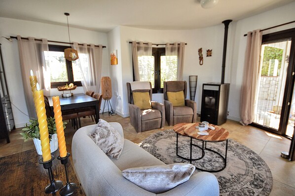 A living room with a sofa, armchairs, a coffee table, and a dining area with a table and chairs.