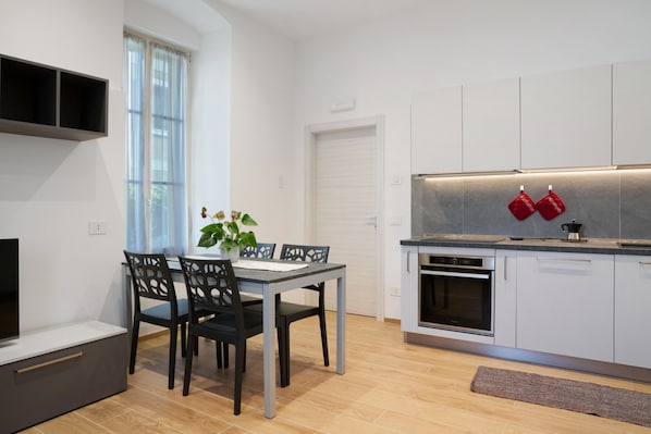 Eine moderne Küche mit Essbereich, eingebauten Geräten und einem großen Fenster.