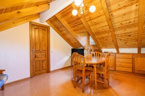 Un espace repas avec une table et des chaises en bois, un lustre et un plafond en bois.