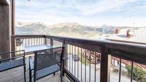 Een balkon met uitzicht op bergen, een tafel en stoelen.
