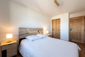 Un dormitorio con cama, mesitas de noche y puertas de madera.