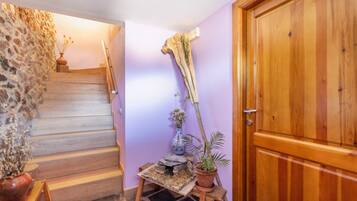 A staircase leading to a room with a wooden door, a small table with a vase and a plant, and a decorative piece on the wall.