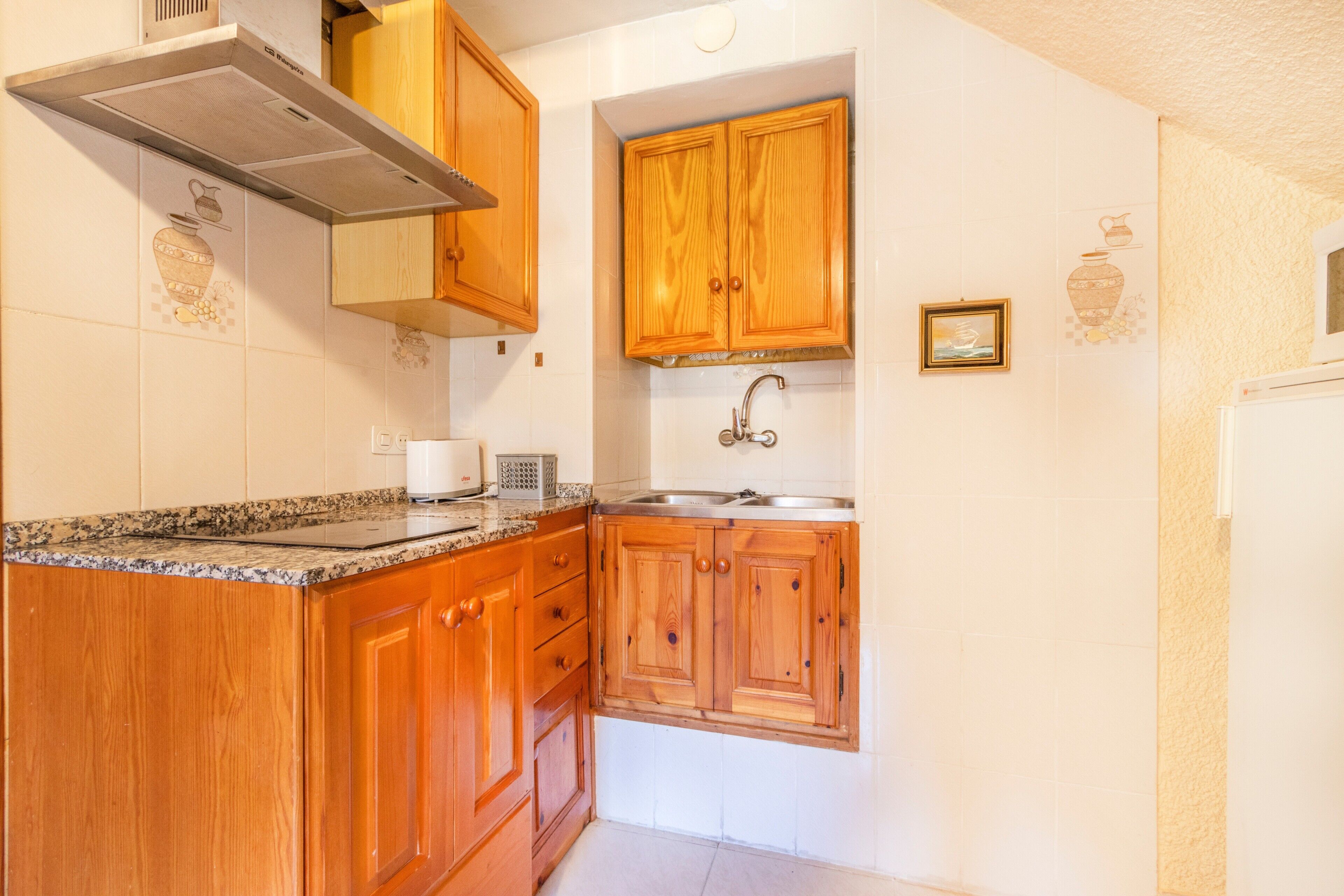 A kitchen with wooden cabinets, a stainless steel sink, and a built-in oven.