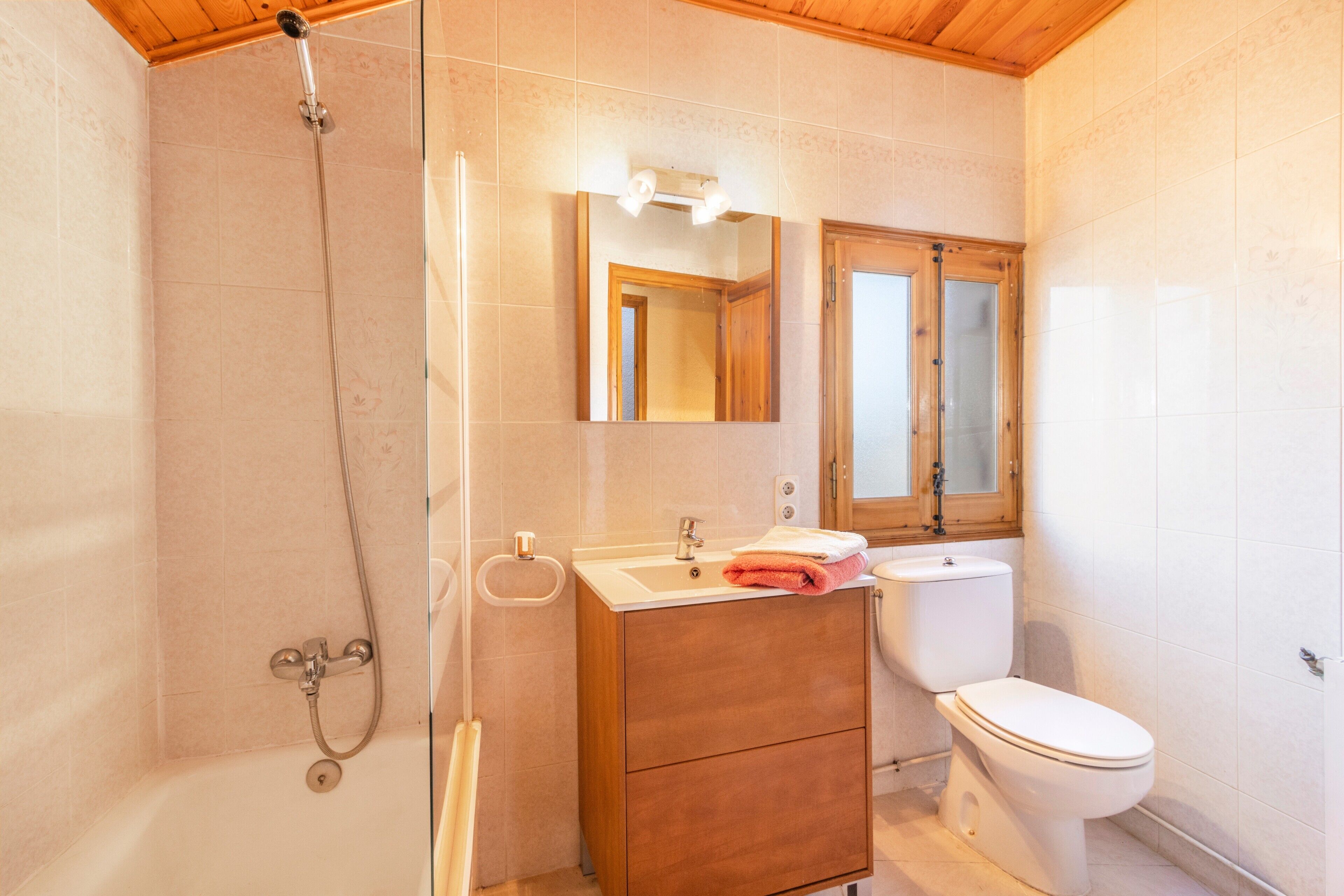 Un baño con ducha, lavabo, espejo e inodoro.