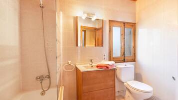 Un baño con ducha, lavabo, espejo e inodoro.
