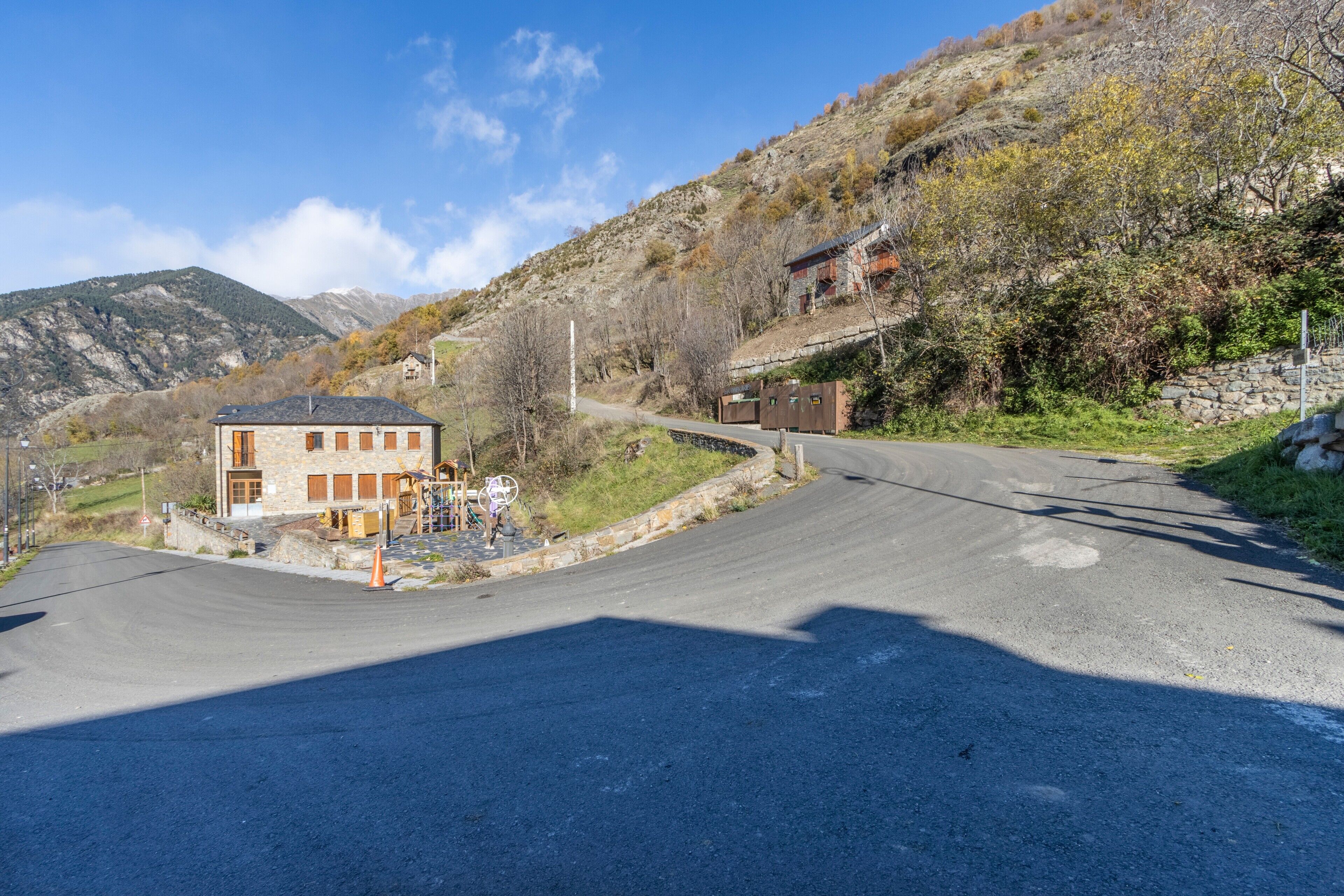 A building with a stone facade, a driveway, and a mountainous backdrop.