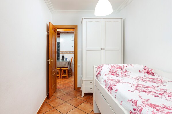 Une chambre à coucher comprenant un lit, une armoire, une petite table avec des chaises et une porte donnant sur une salle de bain.