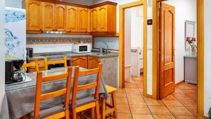 Une cuisine dotée de meubles en bois, d’un four à micro-ondes, d’un évier et d’un coin repas avec une table et des chaises.