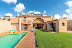 A residential property with a swimming pool, a covered patio, and a well-maintained lawn. - Cottage 'Can Centena' with Private Pool, Wi-Fi and Air Conditioning (Vilamacolum)