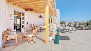 Un patio al aire libre con mobiliario de madera, plantas en macetas y una vista despejada del paisaje circundante.