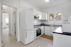 A modern kitchen with white cabinetry, a built-in oven, and a refrigerator.