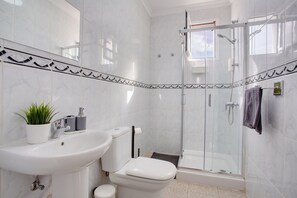 A bathroom with a sink, toilet, and glass-enclosed shower.