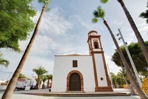A small building with a bell tower, surrounded by palm trees.