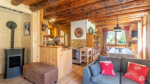 A cozy cabin interior with a wooden interior, a kitchenette, a dining area, and a living room with a sofa and ottoman. - Chalet "Le Petit Ranch" with Mountain View and Private Garden (Le Reposoir)