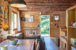 A cozy cabin interior with a dining area, a kitchen, and a view of the outdoors. - Chalet "Le Petit Ranch" with Mountain View and Private Garden (Le Reposoir)