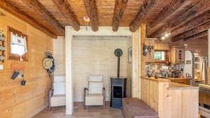 A wooden interior with a bench, chairs, a small stove, and a kitchen area. - Chalet "Le Petit Ranch" with Mountain View and Private Garden (Le Reposoir)