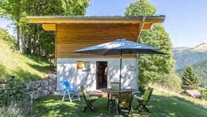 A wooden cabin with a patio, outdoor seating, and a mountain view. - Chalet "Le Petit Ranch" with Mountain View and Private Garden (Le Reposoir)