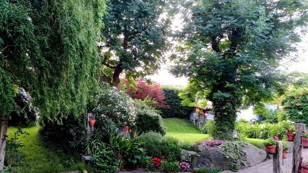 A garden with a paved pathway, various plants, and a stone wall. - Apartment 'Lokate 2 Bedrooms' with Mountain Views, Private Terrace and Wi-Fi (Olaskoegia)
