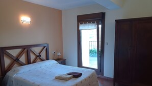 A bedroom with a bed, a nightstand, a wall-mounted light, a door leading outside, and a wardrobe. - Apartment 'Lokate 2 Bedrooms' with Mountain Views, Private Terrace and Wi-Fi (Olaskoegia)