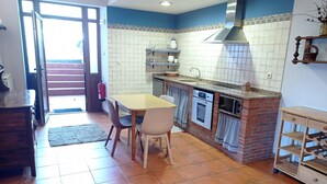 A kitchen with a dining table, chairs, a built-in oven, microwave, and a brick accent wall. - Apartment 'Lokate 2 Bedrooms' with Mountain Views, Private Terrace and Wi-Fi (Olaskoegia)
