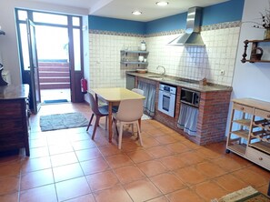 A kitchen with a dining table, chairs, a built-in oven, microwave, and a brick accent wall.