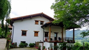 A two-story building with a balcony, potted plants, and a view of the countryside. - Apartment 'Lokate 2 Bedrooms' with Mountain Views, Private Terrace and Wi-Fi (Olaskoegia)