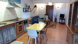 A compact kitchen with a dining area, a sofa, and a television. - Apartment 'Lokate 2 Bedrooms' with Mountain Views, Private Terrace and Wi-Fi (Olaskoegia)