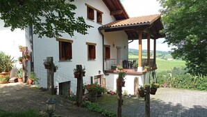 A white building with a balcony, potted plants, and a view of the countryside.