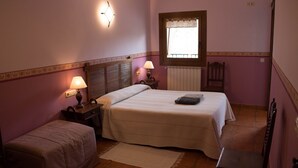 A bedroom with a bed, bedside tables, a window, a radiator, and a chair.