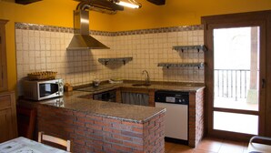 A kitchen with a brick island, a microwave, a dishwasher, and a window to the right.
