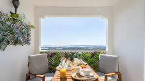 A balcony with a table set for breakfast, chairs, and a view of the city. - Apartment 'Appartement Avec 2 Piscines' with Sea View, Wi-Fi and Air Conditioning (Mutxamel)