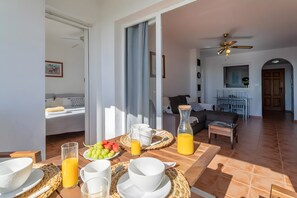 Un coin repas avec une table mise pour le petit-déjeuner, un canapé et un ventilateur de plafond en arrière-plan.