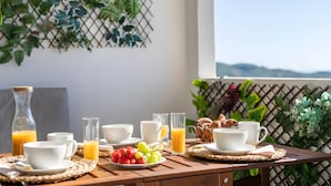 A breakfast table with cups, juice, and pastries on a balcony with a view. - Apartment 'Appartement Avec 2 Piscines' with Sea View, Wi-Fi and Air Conditioning (Mutxamel)