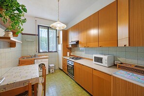 A kitchen with wooden cabinets, a microwave, a sink, and a window.