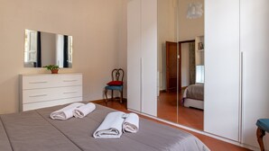 Une chambre à coucher comprenant un lit, une commode, une chaise, un miroir et une armoire.