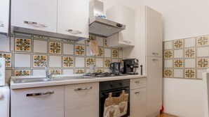 Une cuisine avec des meubles blancs, une cuisinière, un évier et des carreaux décoratifs sur le mur derrière l’évier.