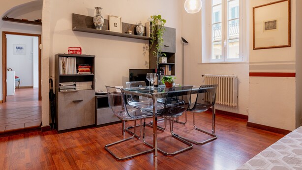 Un espace repas moderne avec une table en verre, des chaises en m étal, une bibliothèque et une plante en pot.