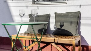 A wooden table with a green metal frame, two wine glasses, and a cushion with a wine glass design. - Apartment 'Ático San Jose' with Shared Terrace, Wi-Fi and Air Conditioning (Cádiz)
