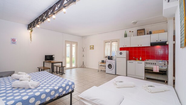 Ein Hotelzimmer mit Bett, Schreibtisch, Waschmaschine und einer Küchenzeile.
