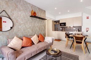 A modern living room with a sofa, coffee table, and a dining area with chairs and a table.