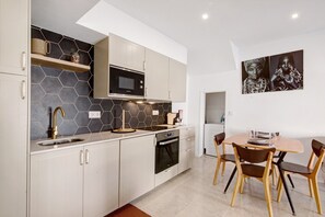 A modern kitchen with white cabinets, a microwave, and a dining area with a table and chairs.