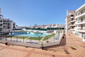 A rooftop pool area with lounge chairs, a swimming pool, and surrounding buildings. - Sousa E Filhos Apartment – Shared Pool, Near the Beach (Albufeira)