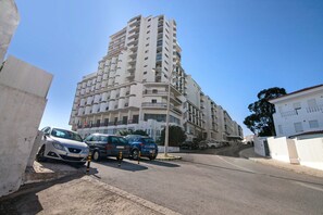 A multi-story residential building with balconies, parked cars, and a clear sky. - Sousa E Filhos Apartment – Shared Pool, Near the Beach (Albufeira)