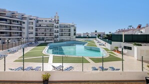 A rooftop swimming pool with lounge chairs, surrounded by apartment buildings. - Sousa E Filhos Apartment – Shared Pool, Near the Beach (Albufeira)