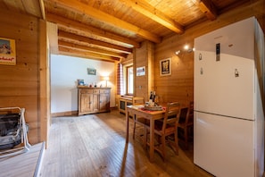 A wooden interior with a kitchen area, including a refrigerator, wooden cabinets, and a dining table with chairs. - Apartment "Le Grand Tétras" with Shared Terrace, Balcony, and Wi-Fi (Flumet)
