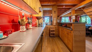 A wooden cabin interior with a kitchen area, wooden cabinets, and a view through the window. - Apartment "Le Chamois" with Shared Terrace, Balcony, and Wi-Fi (Flumet)