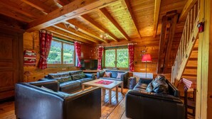 A cozy log cabin interior with a wooden ceiling, leather sofas, a television, and a fireplace. - Apartment "Le Chamois" with Shared Terrace, Balcony, and Wi-Fi (Flumet)