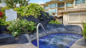 A whirlpool spa surrounded by tropical plants and a building with balconies. - Waipouli Beach Resort A106 Oceanfront 2BD 3BA (Kapaʻa)